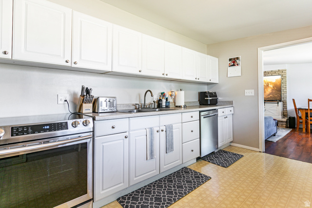 1619 Davis Drive Layton, UT 84041 - Photo 9 of 27 Kitchen featuring white cabinetry, light countertops, stainless steel appliances.