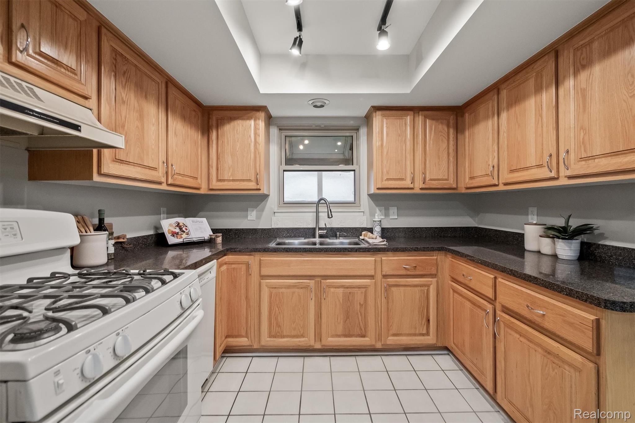 11326 Common Road Warren, MI 48093 - Photo 17 of 35 Kitchen with white range with gas cooktop, light tile patterned flooring, dark stone countertops, and wood finish cabinetry
