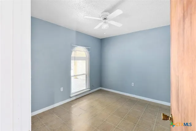 an empty room with windows and fan