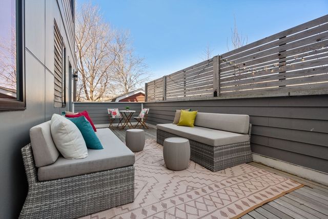 a roof deck with couches and wooden fence