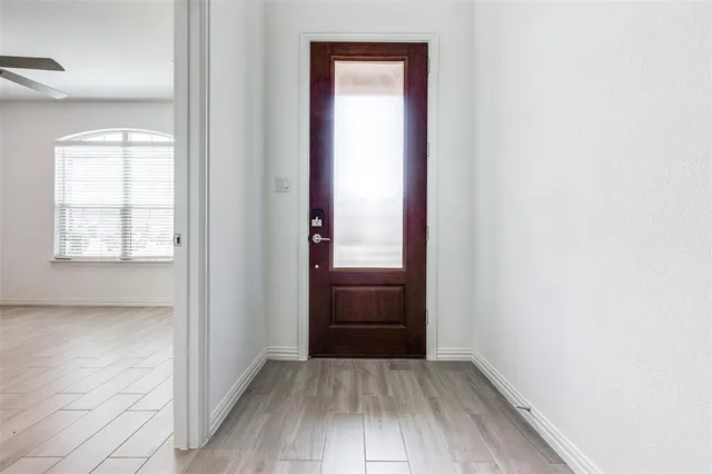 an empty room with wooden floor cabinet and windows