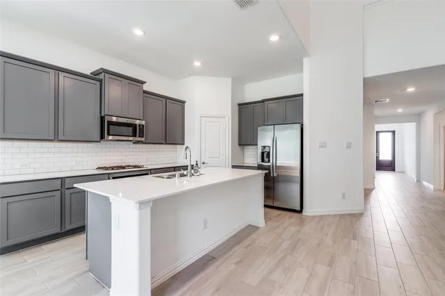 a kitchen with kitchen island a sink stainless steel appliances and cabinets