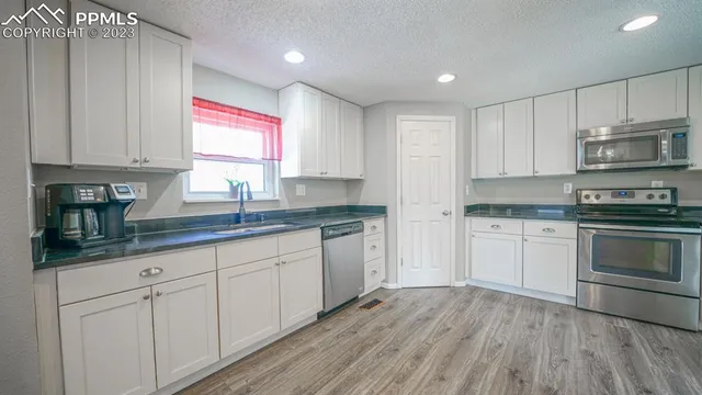a kitchen with granite countertop white cabinets and white appliances