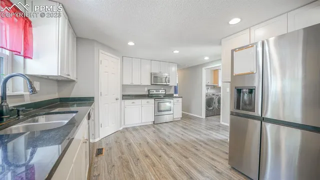 a kitchen with granite countertop a refrigerator stove and sink