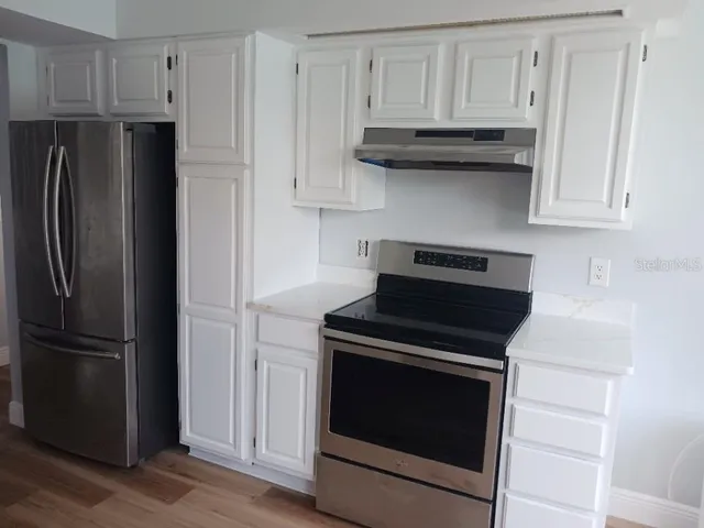 a kitchen with granite countertop white cabinets and stainless steel appliances