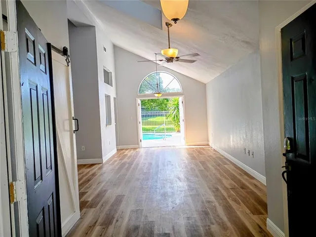 a view of empty room with wooden floor and fan