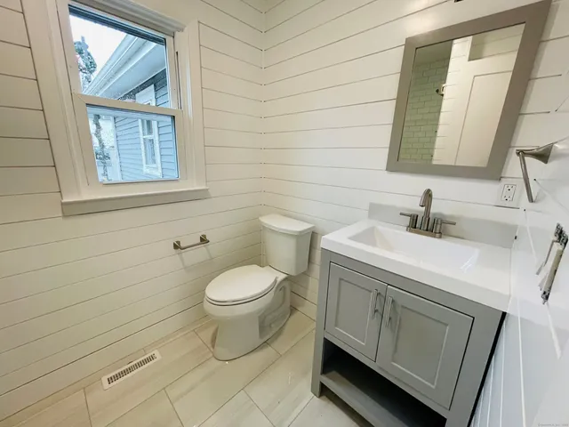 a bathroom with a toilet a sink a mirror and a window