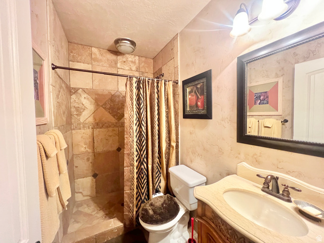 369 Culross Circle Tooele, UT 84074 - Photo 36 of 54 Bathroom featuring a walk-in shower with natural stone-look tile, a single vanity with an integrated sink and bronze-finish faucet, and a decorative framed mirror