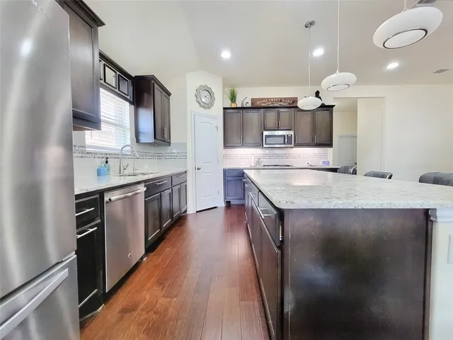 a kitchen with stainless steel appliances granite countertop a sink a stove and a wooden floors