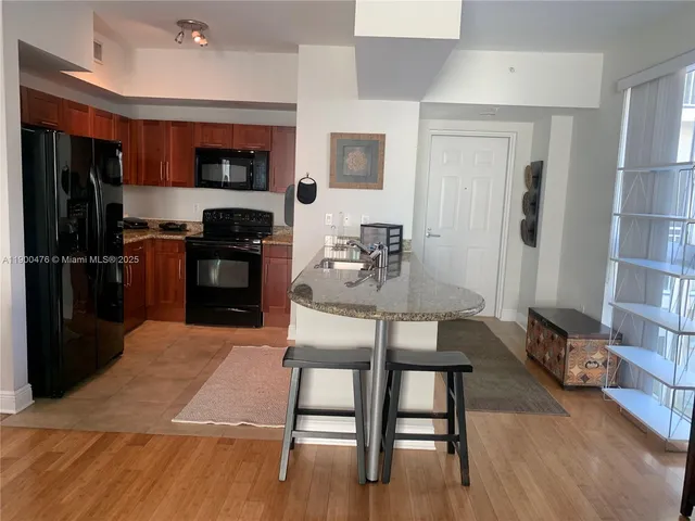 a kitchen with stainless steel appliances granite countertop a stove a refrigerator and a sink with wooden cabinets