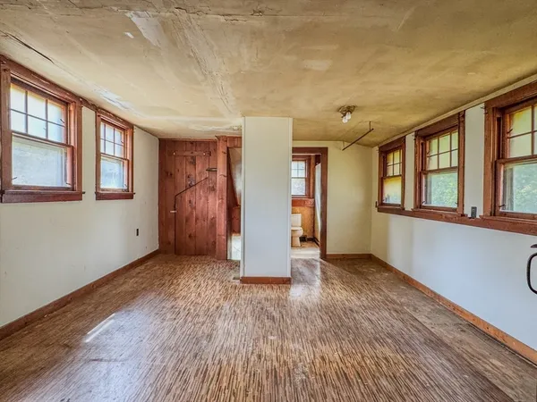a view of an empty room with window and wooden floor