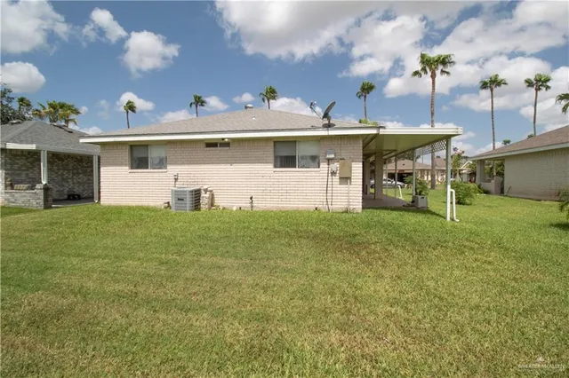 a view of a white house with a big yard and sitting area