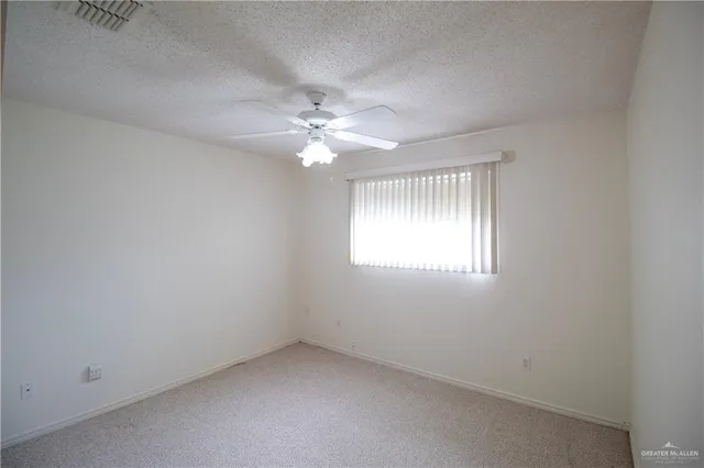 an empty room with chandelier fan and windows