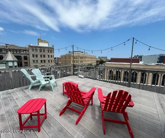 a roof deck with a table and chairs with wooden floor