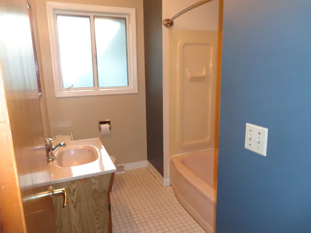a bathroom with a tub sink and mirror