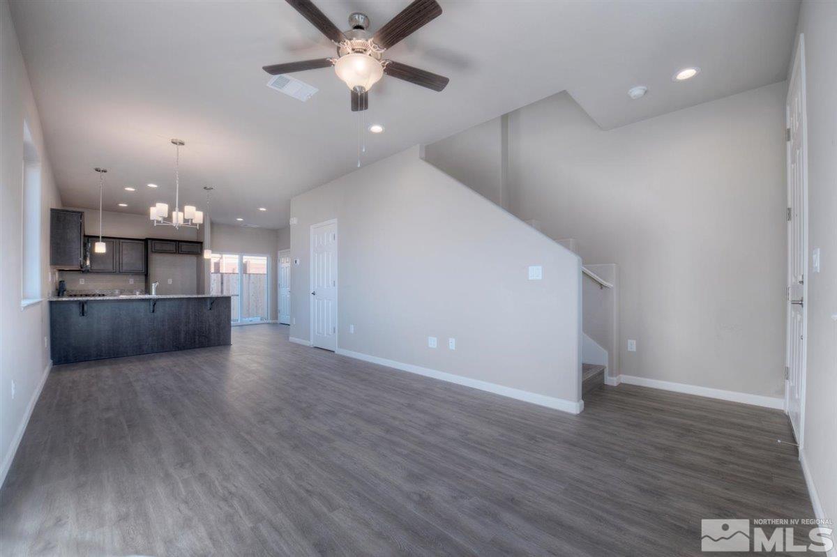 3408 Colonial Downs, Unit LOT 54 Reno, NV 89512 - Photo 2 of 26 an empty room with wooden floor kitchen view and a chandelier
