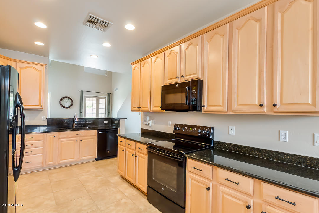 19216 North Lariat Road Maricopa, AZ 85138 - Photo 13 of 40 a kitchen with stainless steel appliances granite countertop a stove a sink and a microwave