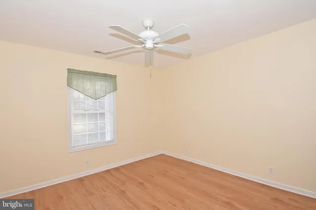 an empty room with a ceiling fan and a window