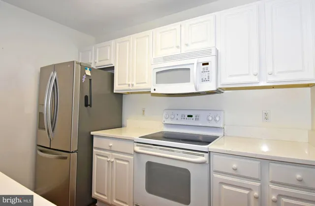 a kitchen with stainless steel appliances white cabinets and a refrigerator