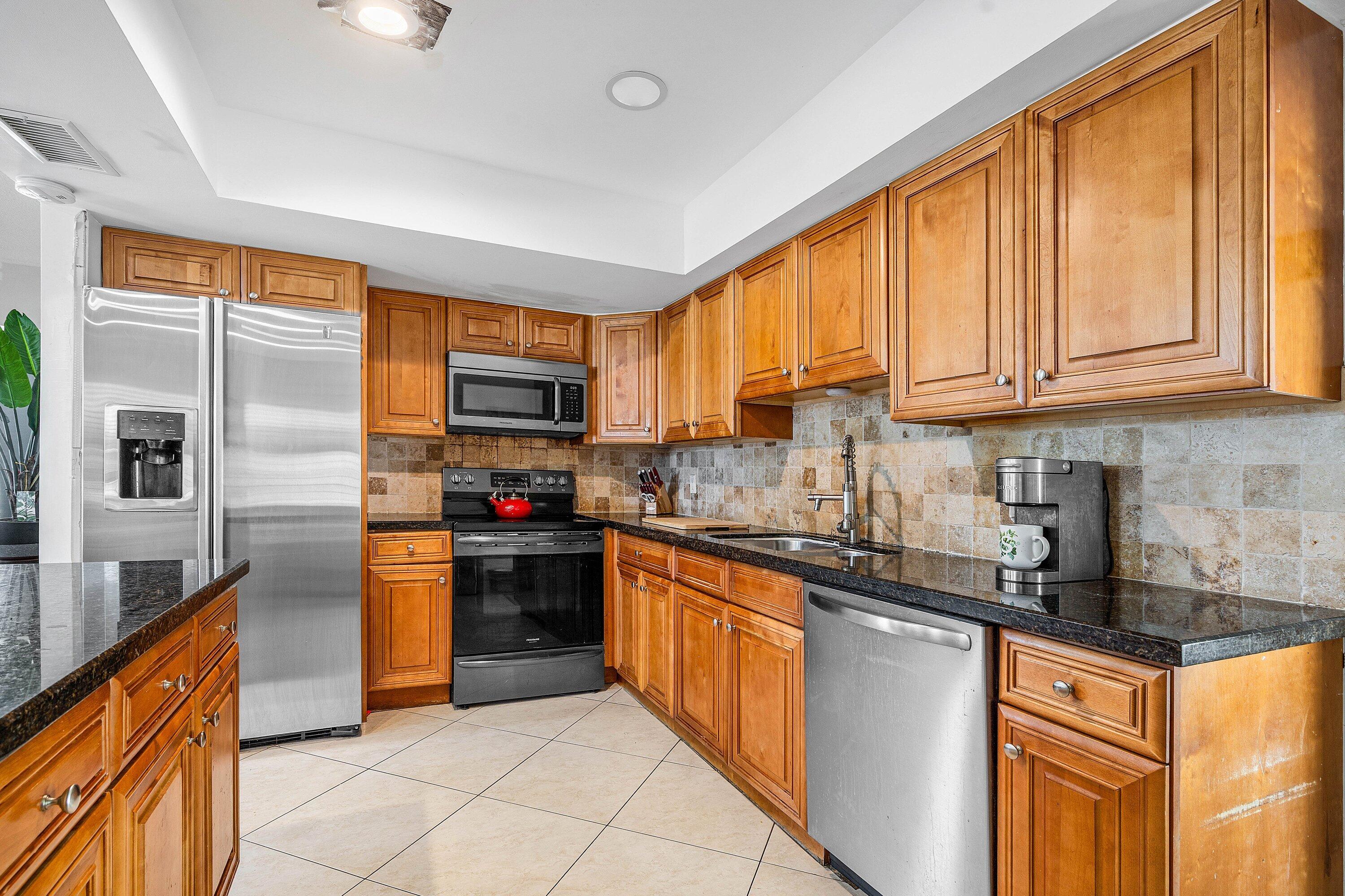 22207 Southwest 65th Terrace Boca Raton, FL 33428 - Photo 12 of 27 a kitchen with stainless steel appliances granite countertop a refrigerator and a stove top oven