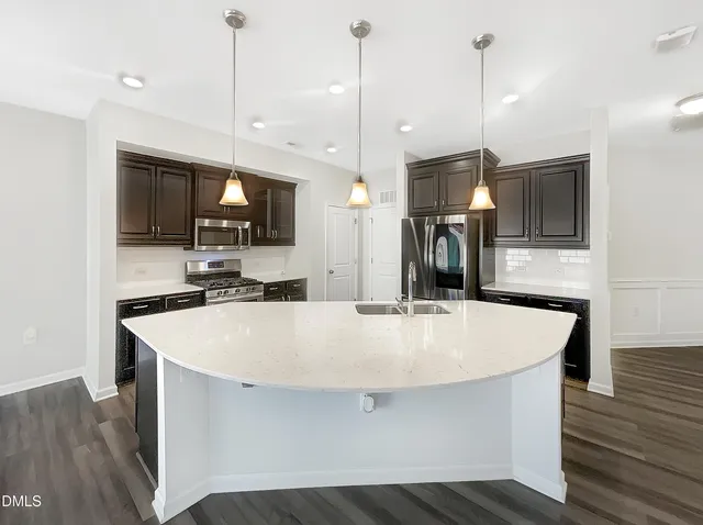 a large kitchen with kitchen island a stove a sink a center island and wooden floor