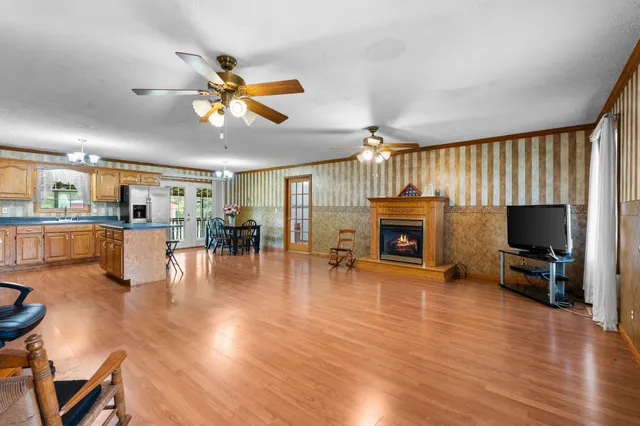a living room with furniture a fireplace a flat screen tv and kitchen view