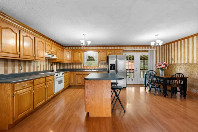 a kitchen with stainless steel appliances granite countertop wooden floors stove top oven and cabinets