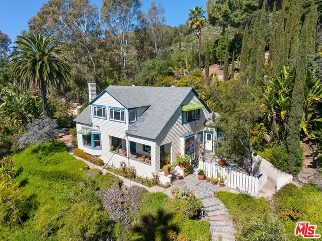 a white house with a large pool and lawn chairs next to a yard