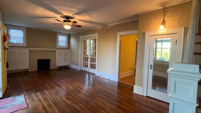 a view of a livingroom with wooden floor a ceiling fan and a kitchen space