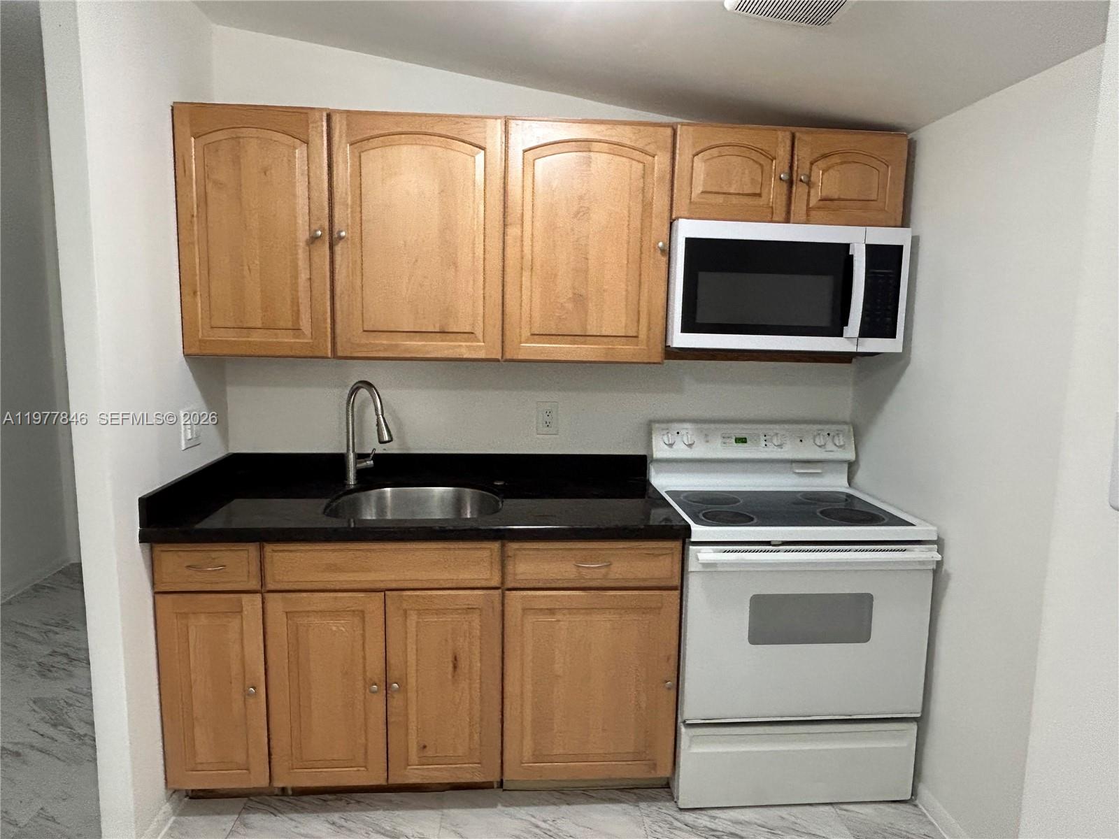 10467 South 228th Lane, Unit A Boca Raton, FL 33428 - Photo 3 of 27 a kitchen with white cabinets and stainless steel appliances
