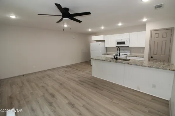 a kitchen with kitchen island a sink stainless steel appliances and white cabinets