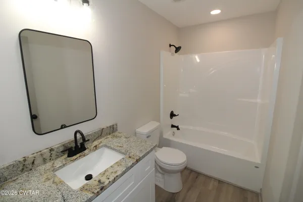 a bathroom with a granite countertop sink toilet and shower
