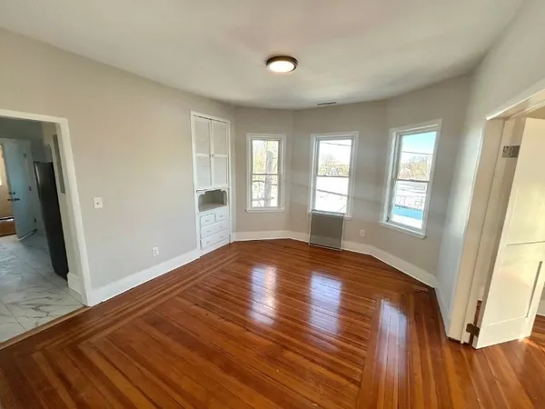 a view of empty room with wooden floor and fan