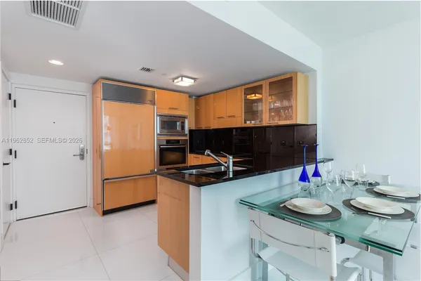 a kitchen with stainless steel appliances kitchen island granite countertop a sink and a refrigerator