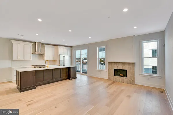 a large kitchen with kitchen island a sink wooden floor and a fireplace