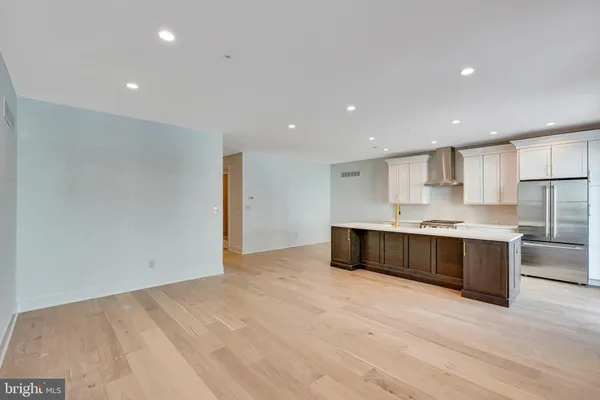 a large white kitchen with kitchen island a sink wooden floor and a large window