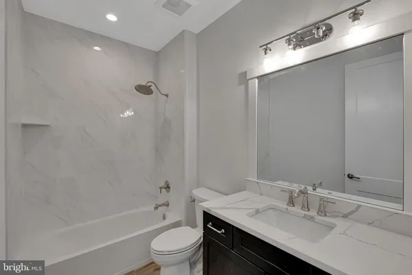 a bathroom with a granite countertop sink toilet and shower