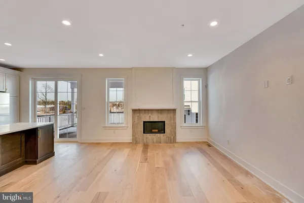 an empty room with wooden floor fireplace and windows