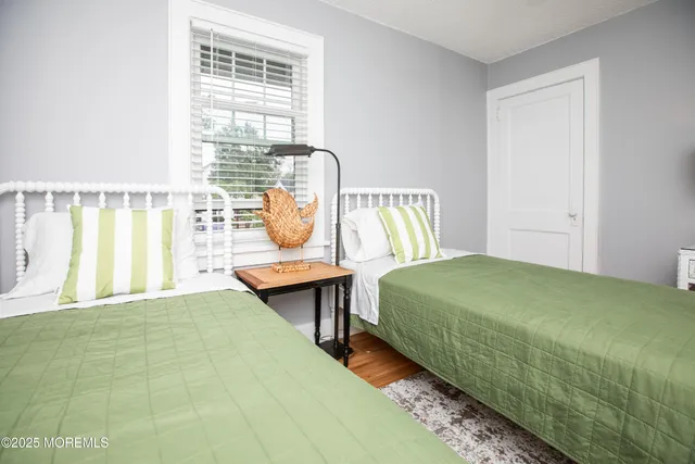 a bedroom with a bed a table and windows