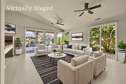 a living room with furniture ceiling fan and a large window