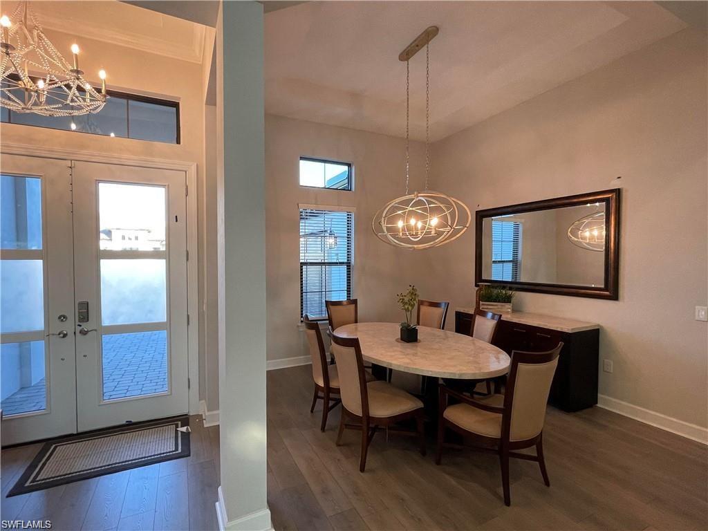 15587 Montello Lane Naples, FL 34114 - Photo 14 of 17 a dining room with furniture a chandelier and wooden floor