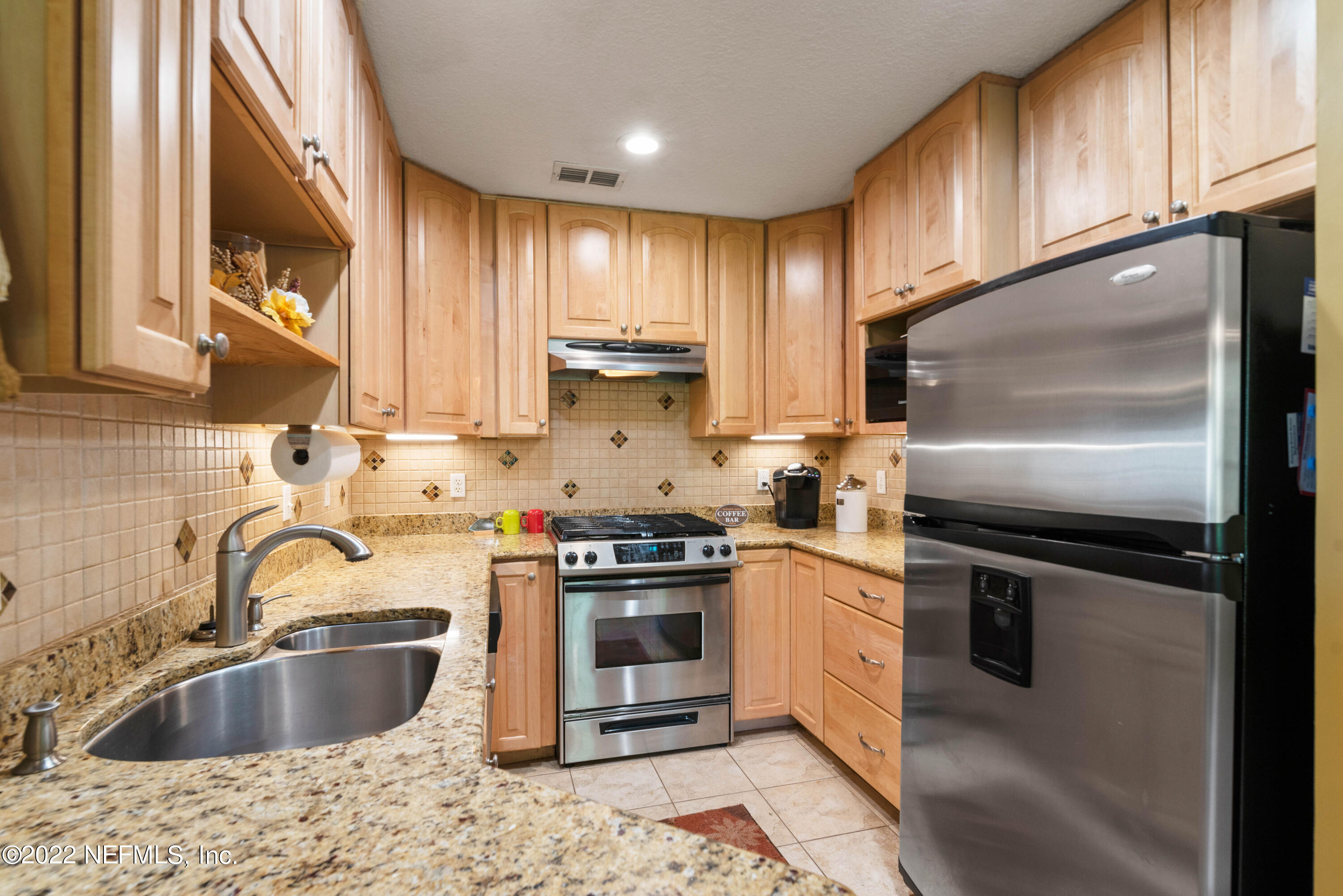 5345 Pine Avenue Fleming Island, FL 32003 - Photo 16 of 39 a kitchen with kitchen island granite countertop a sink stainless steel appliances and cabinets