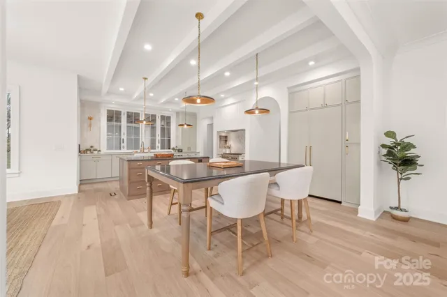 a kitchen with stainless steel appliances kitchen island granite countertop a table chairs in it and wooden floors