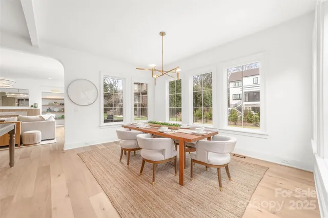 a dining room with wooden floor a chandelier a wooden table and chairs