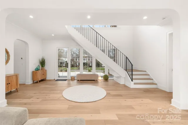 a living room with furniture a chandelier and a dining table with wooden floor