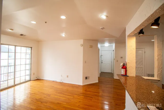 a view of an empty room with wooden floor and windows