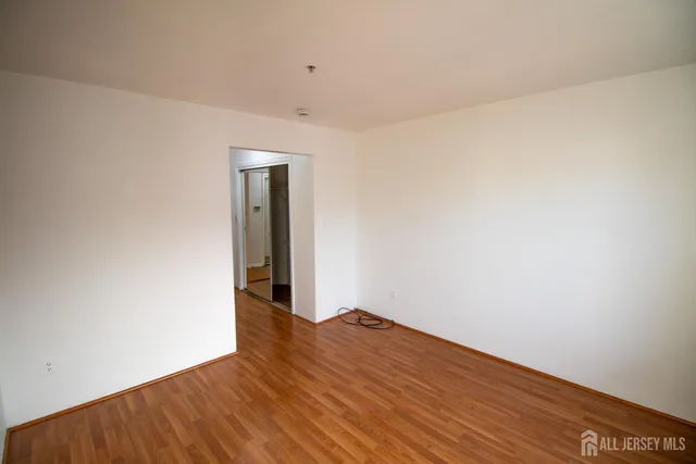 a view of an empty room with wooden floor and closet