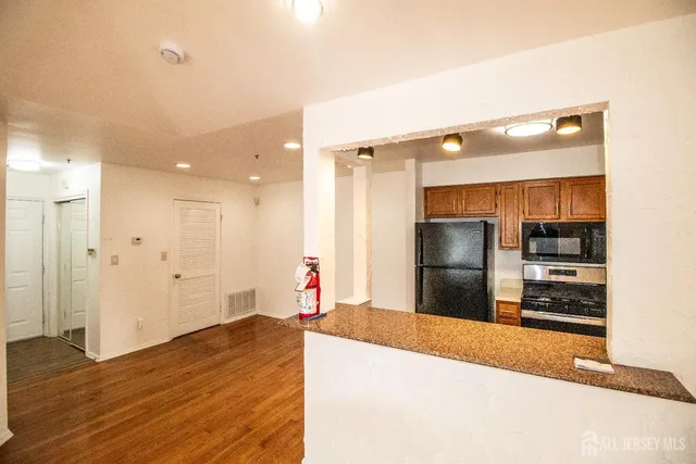 a kitchen with stainless steel appliances kitchen island granite countertop a refrigerator and a sink