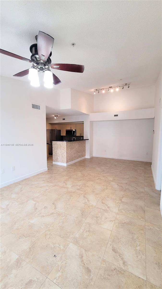 2090 West Preserve Way, Unit 301 Miramar, FL 33025 - Photo 3 of 21 an empty room with kitchen view and a ceiling fan