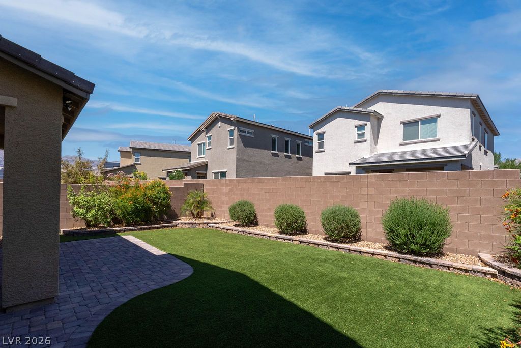 7126 Calvert Cliffs Street North Las Vegas, NV 89084 - Photo 40 of 44 A neatly manicured yard offers a paver patio and verdant lawn, ideal for outdoor living.